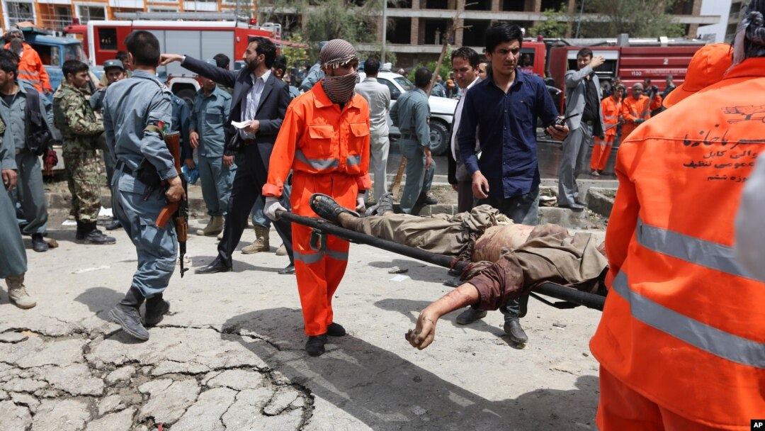 An Afghan municipality worker carries the body of a Taliban after clashes in front of the Parliament, in Kabul, Afghanistan, June 22, 2015. 