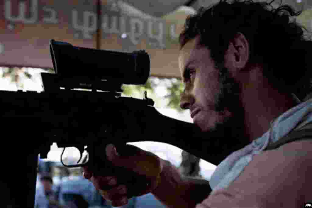 RETRANSMISSION TO ADD BYLINE - In this Wednesday, Aug. 17, 2011 photo, a Libyan rebel sniper peers through his scope in Sabratha, 50 miles (75 kilometers) west of Tripoli, Libya. (AP Photo/Giulio Petrocco)