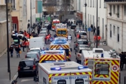 FILE - Ambulances gather in the street outside the French satirical newspaper Charlie Hebdo's office, in Paris, Jan. 7, 2015. Masked gunmen stormed the offices of a French satirical newspaper Wednesday, killing at least 11 people before escaping,