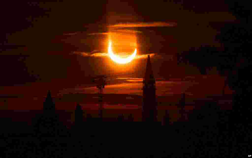 An annular solar eclipse can be seen rising over construction cranes and the Peace Tower on Parliament Hill in Ottawa, Canada.
