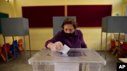 A woman casts her ballot at a polling station during Turkish Cypriots election in the north part of the divided capital Nicosia, Cyprus, Oct. 18, 2020. 