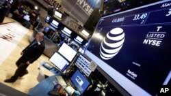 A trader walks by the post that handles AT&T on the floor of the New York Stock Exchange, March 6, 2015.