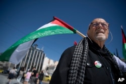 FILE—A man holds a Palestinian flag during a protest rally at Syntagma Square, central Athens, Greece, Saturday, March 30, 2024.