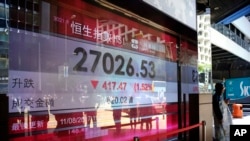 A man walks past an electronic board displaying the Hong Kong share index outside a local bank in Hong Kong, Aug. 11, 2017. 