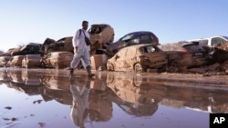 Un hombre camina al lado de automóviles apilados tras las inundaciones en Catarroja, Valencia, España, el 12 de noviembre de 2024. (AP/Alberto Saiz)