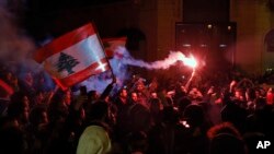 Anti-government demonstrators hold flares and Lebanese flags, during a protest on a road leading to the parliament building in Beirut, Lebanon, Jan. 16, 2020. 