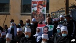 Druse supporters of Syrian President Bashar Assad display display pictures of him during a rally close to the Syrian border demanding the return of the Golan Heights, captured by Israel in 1967, in Majdal Shams, Golan Heights, Feb. 14, 2021.