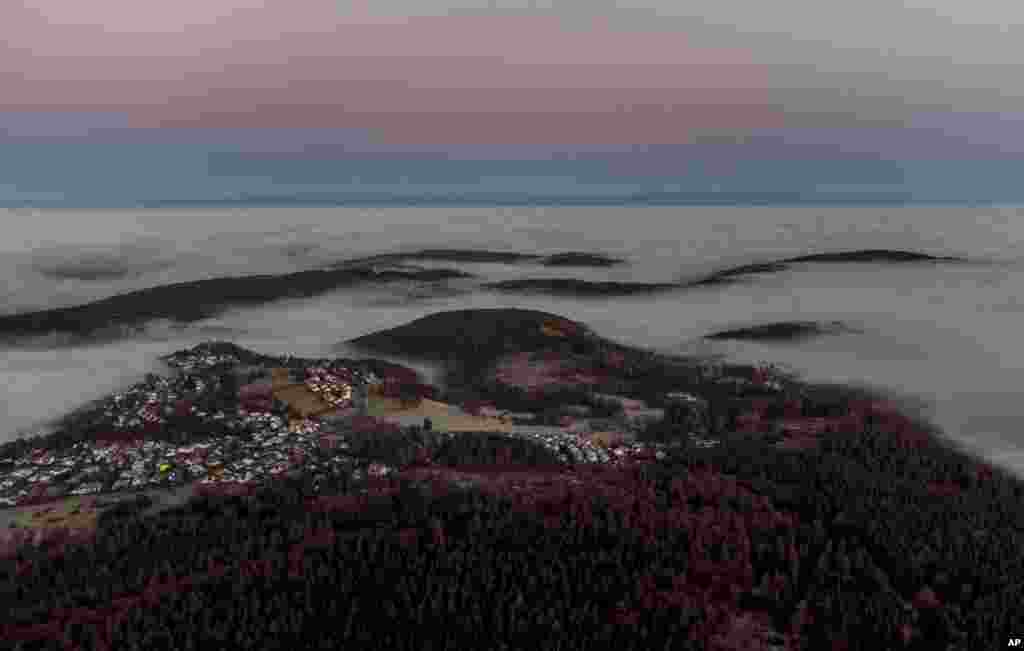 Awan dan kabut terlihat di atas desa-desa di perbukitan Taunus di pinggiran kota Frankfurt, Jerman, Selasa, 24 November 2020 (Foto: AP).