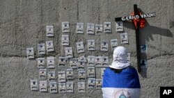 Un manifestante con la bandera nacional mira fotos de manifestantes que murieron durante las protestas contra el gobierno del presidente nicaragüense Daniel Ortega el año pasado, después de un servicio religioso. Managua, Nicaragua, el 2 de noviembre de 2019.