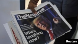A man brings in newspapers with front page photos of President-elect Donald Trump at an office in Dubai, United Arab Emirates, Nov. 10, 2016. 