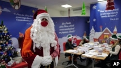 A postal worker dressed as Santa, talks with co-workers as they open envelopes addressed to ‘Pere Noel’ - Father Christmas in French - decorated with love hearts, stickers and glitter, in Libourne, southwest France, Nov. 23, 2020.