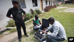 Wani Dansanda yake bada kariya ga jami'in hukumar zabe dake tantance kayan rijistar masu zabe a Legas.