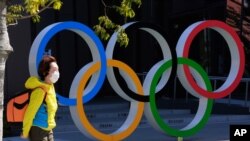 Una mujer pasa junto a los anillos olímpicos en Tokio, el miércoles 10 de marzo de 2021.