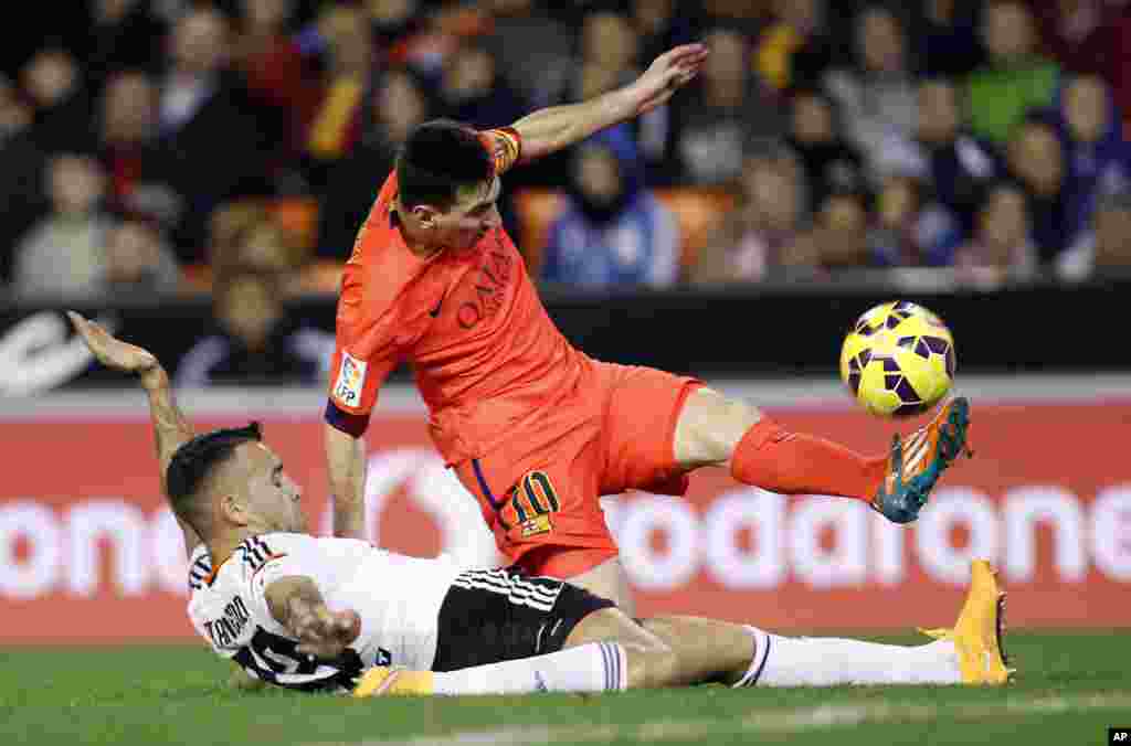 Lionel Messi de Barcelone, de l&#39;Argentine, en haut, engagé dans un duel avec Otamendi de Valence lors d&#39;un match de football de La Liga espagnole au stade Mestalla à Valence, en Espagne, le dimanche 30 novembre 2014.