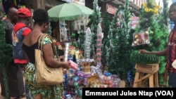 Marché central de Yaoundé, une femme négocie le prix du sapin, à Yaoundé, le 13 décembre 2018. (VOA/Emmanuel Jules Ntap)