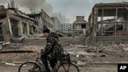 FILE - A man rides on a bike in front of the mail office which was destroyed by a Russian airstrike in Kurakhove, Donetsk region, Ukraine, on Nov. 7, 2024.