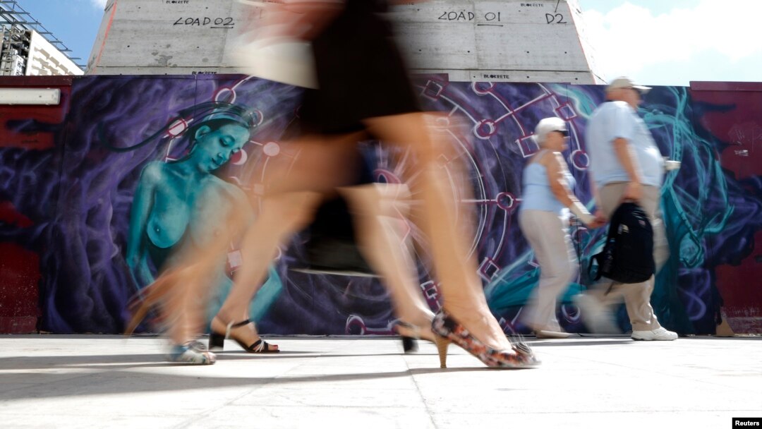 Pejalan kaki melewati grafiti yang dilukis untuk meningkatkan kesadaran akan Kanker Payudara, di Valletta, Malta, Oktober 2013.