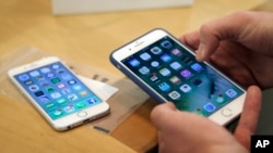 FILE - A customer setting up his new iPhone 7 Plus (R) as he switches from the iPhone 6 at the Apple Store on Michigan Avenue, Chicago, IL., during the release of the Apple iPhone 7, Sept. 16, 2016. 