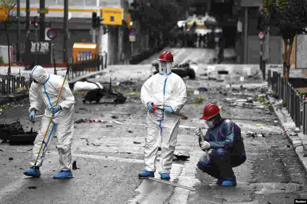 Forensic experts search for evidence on a street where a car bomb went off in Athens, April 10, 2014. 