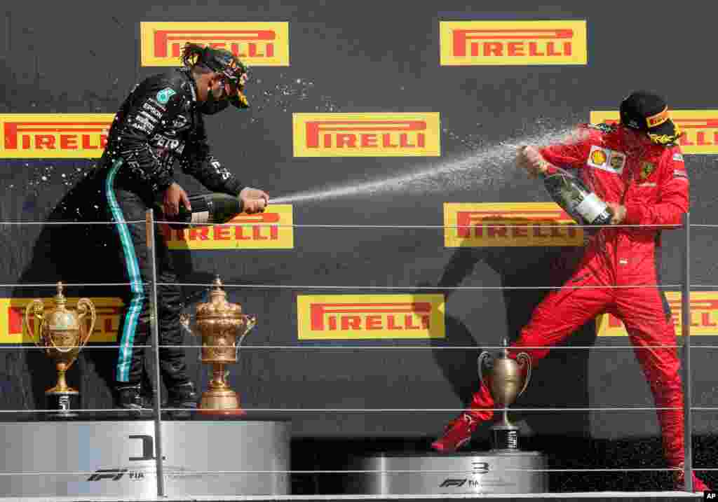 Mercedes driver Lewis Hamilton of Britain, left, sprays champagne at third placed Ferrari driver Charles Leclerc of Monaco after winning the British Formula One Grand Prix at the Silverstone racetrack, Silverstone, England.