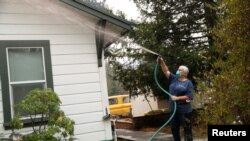 Vicki Nightingale sprays water on her home in Glen Ellen, California, Oct. 11, 2017.