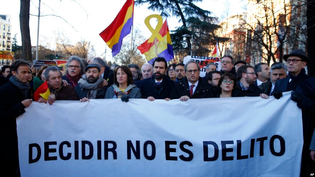 Presiden Parlemen Catalonia, Roger Torrent (tengah) dan Presiden regional Catalan Quim Torra (kanan tengah), memegang spanduk bertuliskan dalam bahasa Spanyol: "Memilih Bukan Kriminal", di luar Mahkamah Agung Spanyol di Madrid, Selasa, Februari 12, 2019.