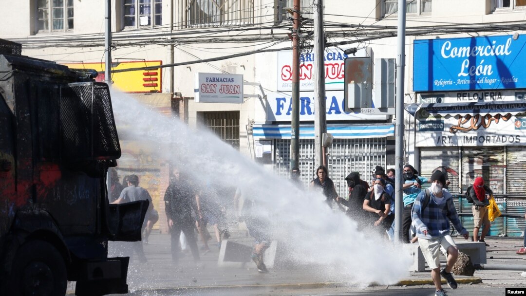 Demonstrators are sprayed by riot police with a water cannon during a protest against Chile's government in Valparaiso, Oct. 28, 2019. 