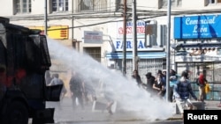 Demonstrators are sprayed by riot police with a water cannon during a protest against Chile's government in Valparaiso, Oct. 28, 2019. 