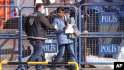 FILE-A masked Turkish police officer escorts a migrant after the first vessel transporting migrants from Greek island of Lesbos was docked in Dikili port, Turkey, putting into practice a European Union plan to stem migration to Europe, April 4, 2016.