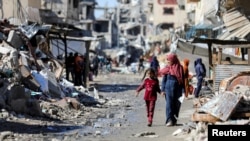Palestinos caminan junto a las ruinas de casas destruidas durante la ofensiva militar de Israel, en medio del conflicto en curso entre Israel y Hamás, en la ciudad de Gaza, el 20 de marzo de 2024. La ONU ha condenado los ataques "cada día, esta guerra cobra más víctimas civiles".