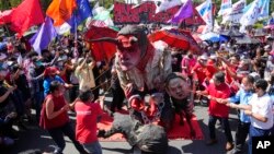 FILE - Activists destroy an effigy of Philippine President Rodrigo Duterte, center, with his daughter Davao city mayor, Sara, right, and Ferdinand 'Bongbong' Marcos Jr., son of the late dictator, during a protest in Quezon City, Philippines, Dec. 10, 2021.