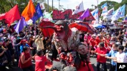 Aktivis menghancurkan patung Presiden Filipina Rodrigo Duterte, tengah, dengan putrinya wali kota Davao, Sara, kanan, dan Ferdinand 'Bongbong' Marcos Jr., putra mendiang diktator Ferdinand Marcos. (Foto: AFP)