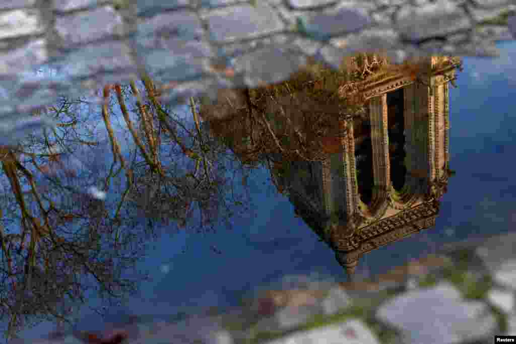 The towers of the Notre-Dame de Paris Cathedral, which was ravaged by a fire in 2019, are reflected in a puddle ahead of the reopening ceremonies, in Paris, France.