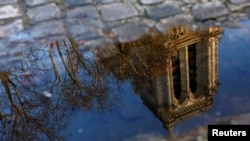 The towers of the Notre-Dame de Paris Cathedral, which was ravaged by a fire in 2019, are reflected in a puddle ahead of the reopening ceremonies, in Paris, France.