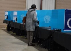 FILE - A Georgia voter marks a ballot during the first day of early voting in the U.S. Senate runoffs at the Gwinnett County Fairgrounds, in Atlanta, Georgia, Dec. 14, 2020.