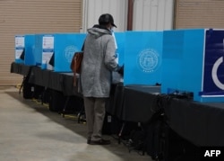 FILE - A Georgia voter marks a ballot during the first day of early voting in the U.S. Senate runoffs at the Gwinnett County Fairgrounds, in Atlanta, Georgia, Dec. 14, 2020.