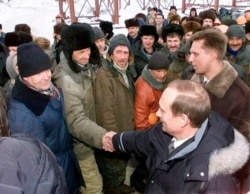FILE - Acting President Vladimir Putin shakes hands with workers during his visit to an oil and gas field in Surgut, western Siberia, Russia, March 3, 2000.