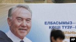 A man walks past an election poster of Kazakh President Nursultan Nazarbayev in Almaty, Feb. 22, 2011.