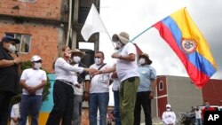 Rodrigo Granda, a la derecha, excomandante rebelde y miembro del partido político FARC, le da la mano a Rocío López, hermana de dos secuestrados, durante una ceremonia en la zona rural de Pipiral cerca de Villavicencio, Colombia, el 29 de octubre de 2020.