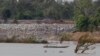 FILE - A fishing boat passes near a construction site of the Don Sahong dam, near the Cambodia-Laos border, June 20, 2016.