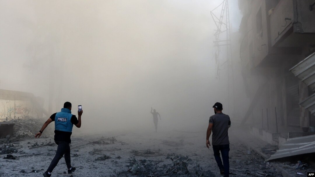 Warga dan seorang jurnalis tampak berlari menuju lokasi ledakan menyusul serangan Israel yang menargetkan sebuah sekolah di distrik Zeitoun, Jalur Gaza, pada 1 September 2024. (Foto: AFP/Omar Al-Qattaa)