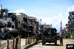 FILE - Soldiers are seen on truck among destroyed buildings in Marawi City, southern Philippines, May 23, 2019.