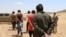 FILE - Men, who the Democratic Forces of Syria fighters claimed were Islamic State fighters, walk as they are taken prisoners after SDF advanced in the southern rural area of Manbij, in Aleppo Governorate, Syria, May 31, 2016. 