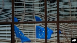 European Union flags are reflected in a window of the European Council in Brussels, Dec. 19, 2020. The European Union and the United Kingdom were making a "last attempt" to clinch a post-Brexit trade deal Saturday.