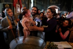 ROMANIA -- Priest Nicolae Ganga (C) baptizes a child during a mass Orthodox baptism ceremony at a church in the Bora neighborhood in Slobozia, November 29, 2012.