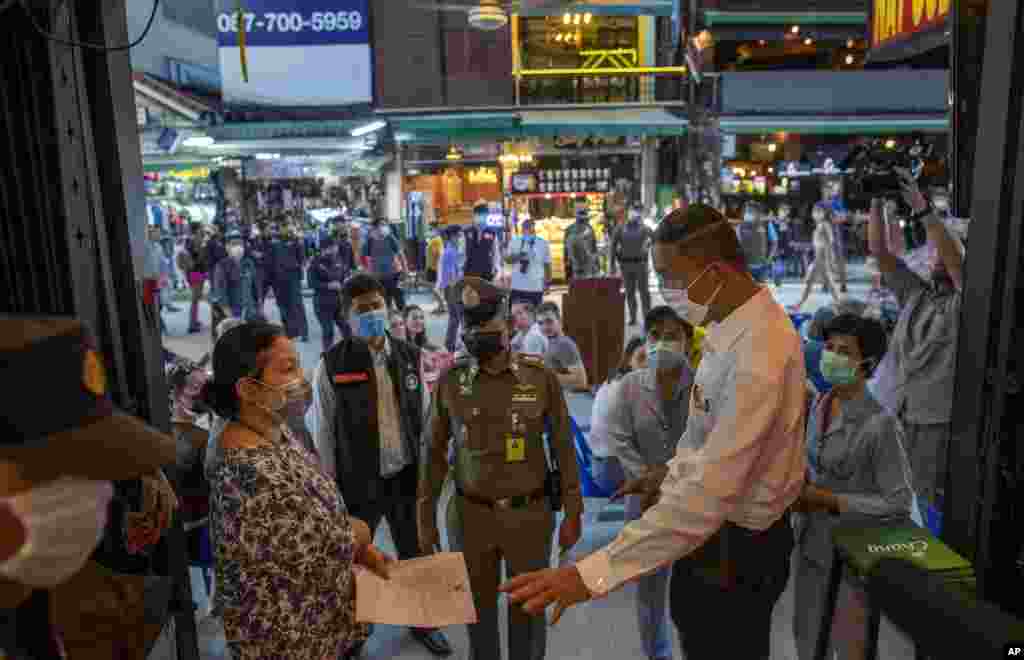 Los funcionarios tailandeses notifican al dueño de un bar del cese de sus operaciones en Khao San Road, un lugar popular entre los turistas extranjeros en Bangkok, Tailandia.