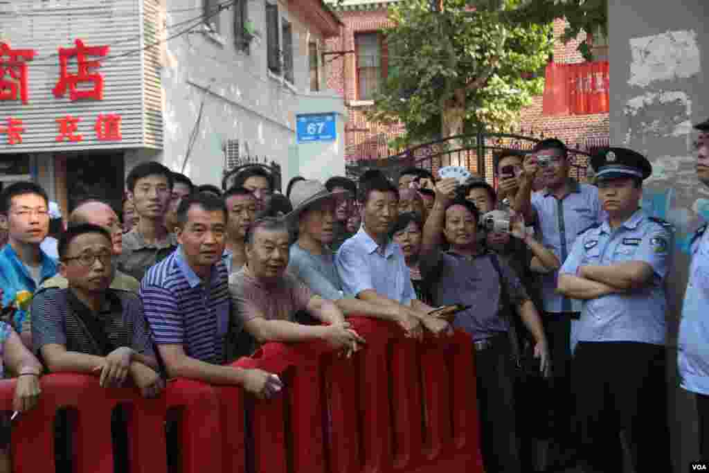 A supporter holds a placard during a rally behind a police barricade near the Jinan Intermediate People&#39;s Court, August 22, 2013. (Dongfang/VOA)