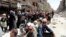 FILE - Residents wait to receive food aid distributed by the U.N. refugee agency at the Palestinian refugee camp of Yarmouk, south of Damascus, Syria, May 2014.