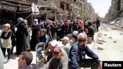 FILE - Residents await food aid distributed by the U.N. refugee agency at the Palestinian refugee camp of Yarmouk, south of Damascus, Syria, May 2014.