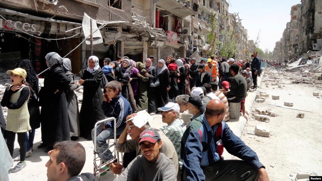 Warga mengantre bantuan makanan PBB di kamp pengungsi di Yarmouk, bagian selatan Damaskus, Suriah. (Foto: Dok)